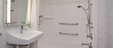 Un baño con lavamanos blanco, bañera y ducha con varios grifos.