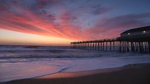 A pier extending into the ocean at sunset with waves crashing onto the shore. - Holiday Inn Express Kitty Hawk Outer Banks by IHG (Kitty Hawk)