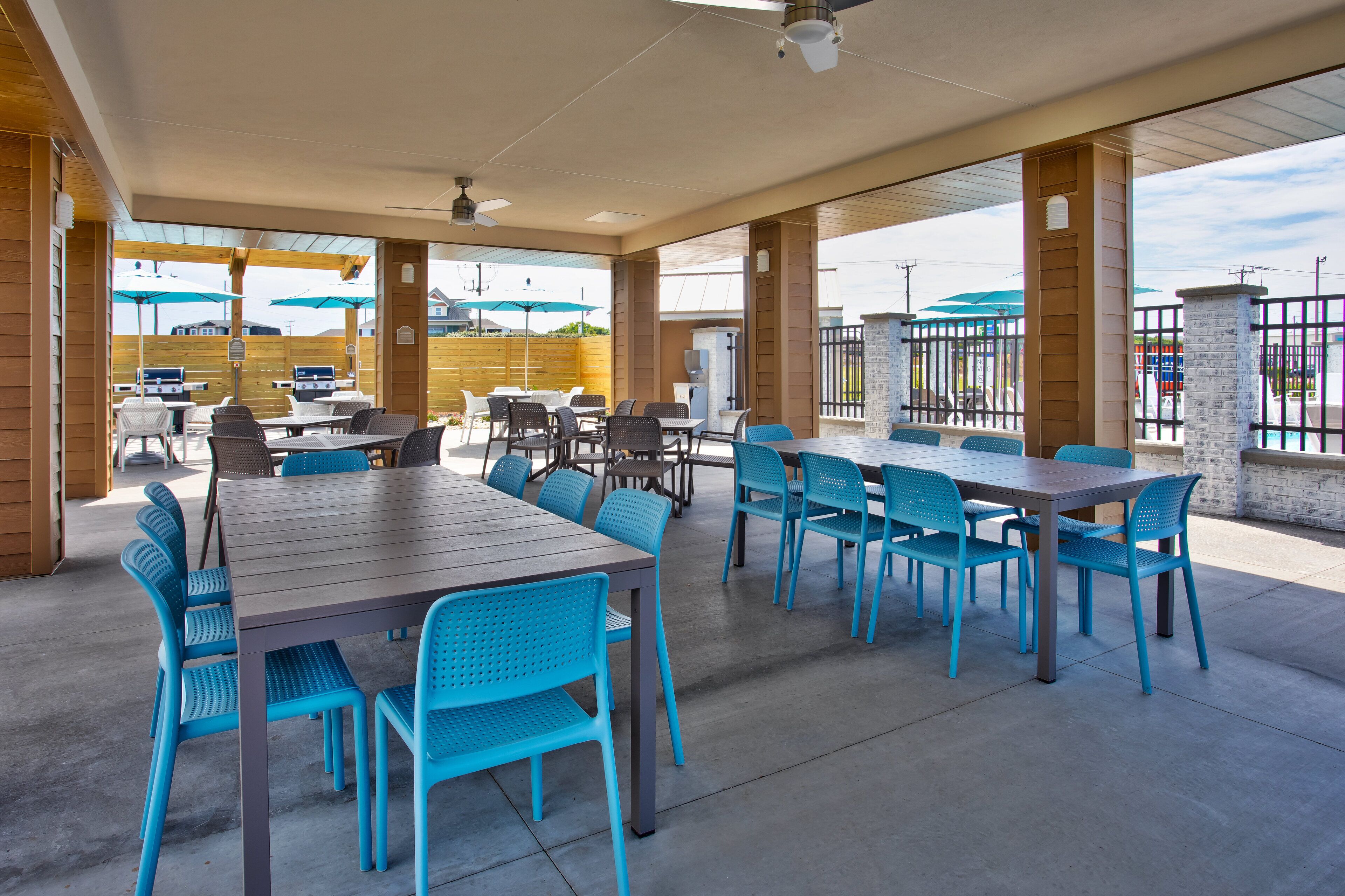 An outdoor patio area with multiple tables and chairs, a covered seating area, and a view of the surrounding area.