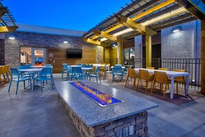 An outdoor patio with seating, a fire feature, and a TV mounted on the wall. - Holiday Inn Express Kitty Hawk Outer Banks by IHG (Kitty Hawk)