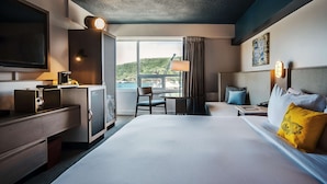 Habitación de hotel con una cama grande, un escritorio, una silla y vistas al exterior.
