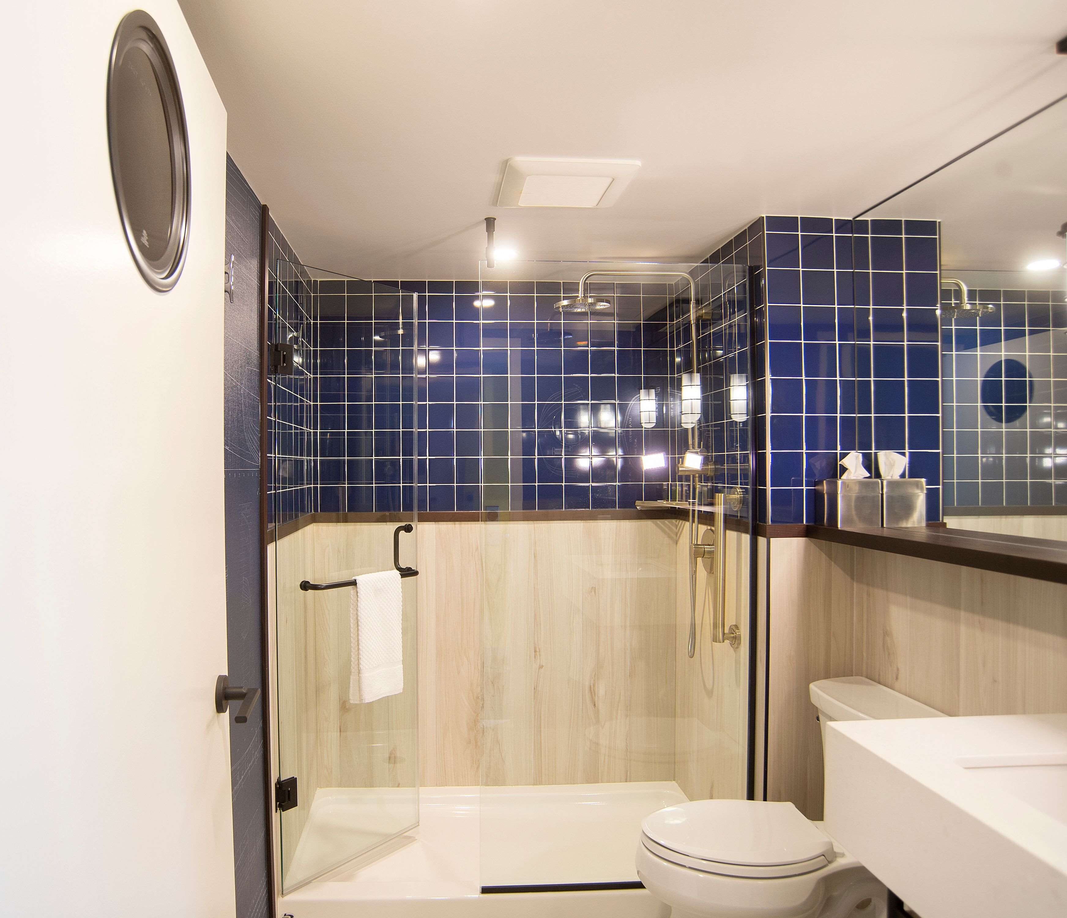 Ein modernes Badezimmer mit einer ein Glasfach raumteilenden Dusche, einer weißen Toilette und einem Waschbecken mit Spiegel darüber.
