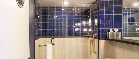 A modern bathroom with a glass-enclosed shower, a white toilet, and a sink with a mirror above it.