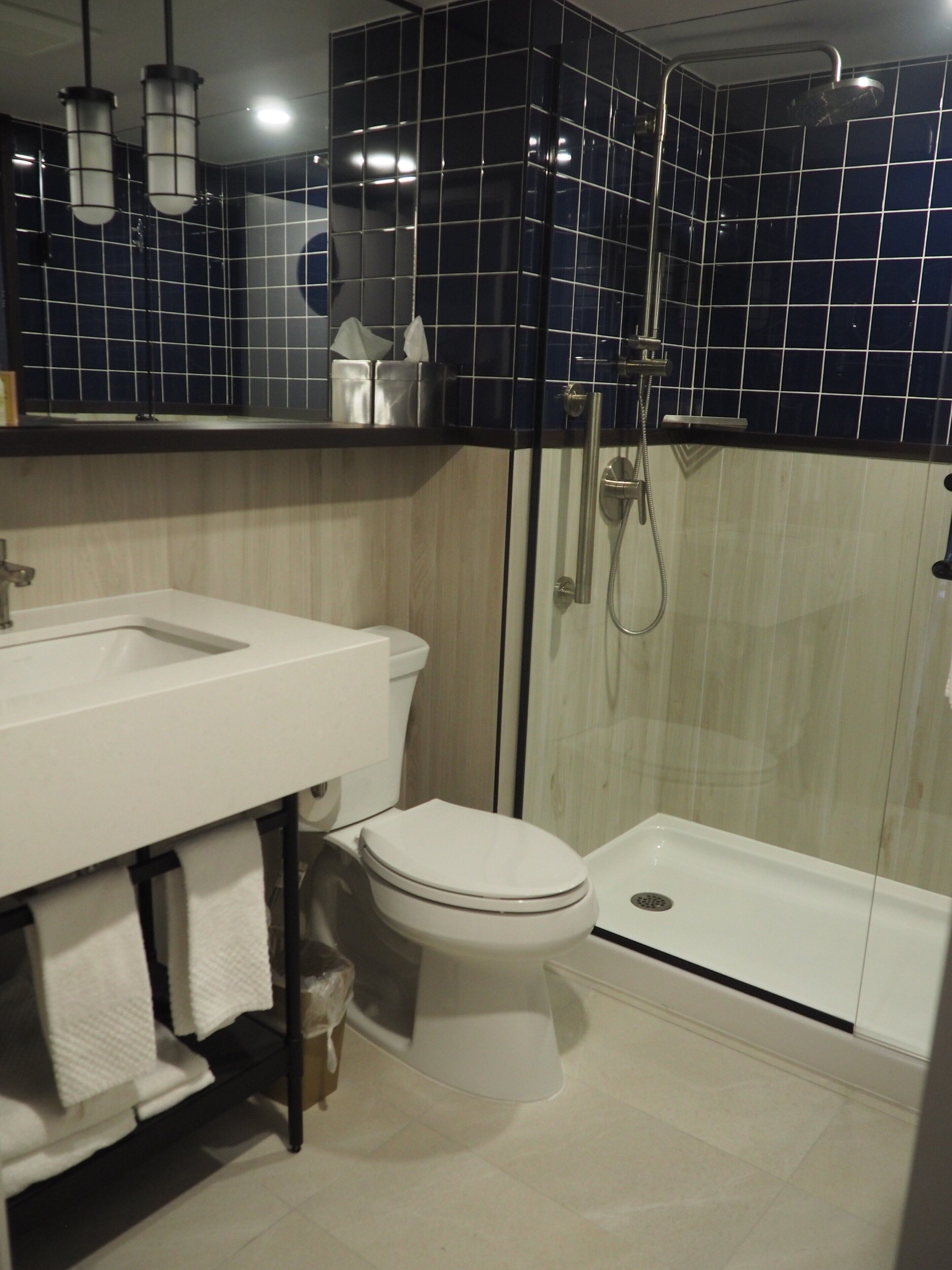 Casa de banho moderna com lavatório, sanita e chuveiro, tudo em branco.