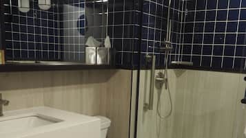 Casa de banho moderna com lavatório, sanita e chuveiro, tudo em branco.