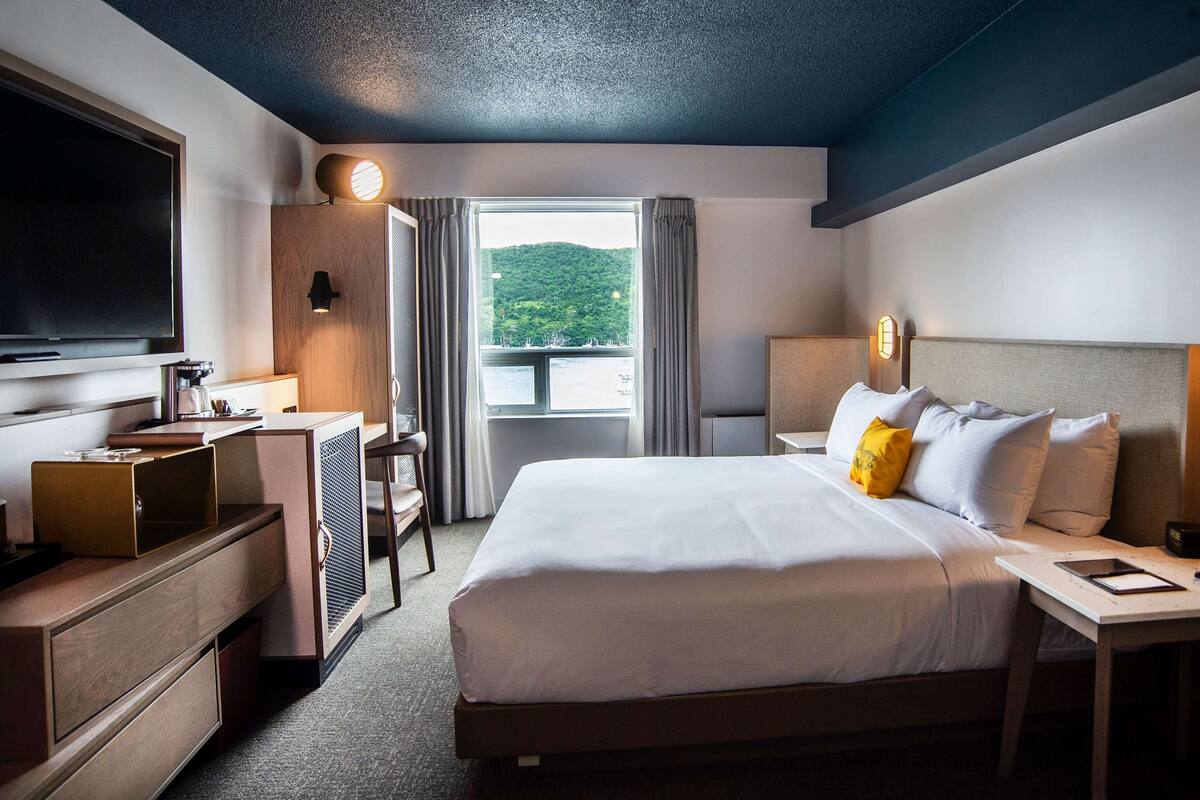 A hotel room with a large bed, a desk with a computer, a TV, and a view of the outdoors.