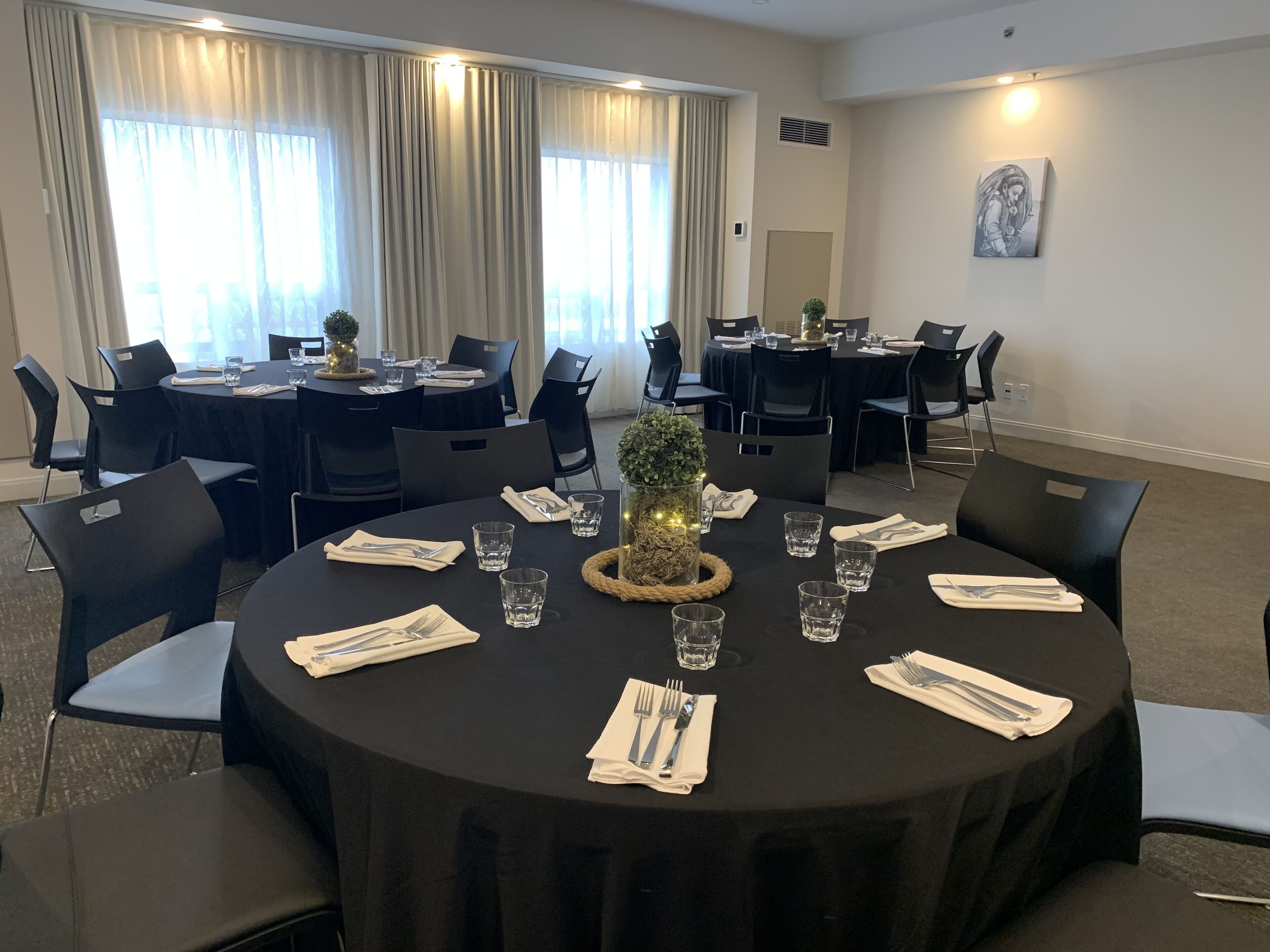 A conference room with round tables, black chairs, and a decorative centerpiece.