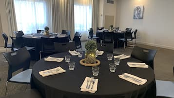 A conference room with round tables, black chairs, and a decorative centerpiece.