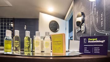 A bathroom counter with various toiletries and a sign indicating complimentary items.