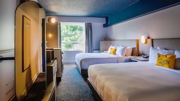A hotel room with two beds, a desk, a chair, and a window with curtains.