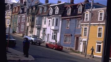 Vista de una calle con casas coloridas, un agente de policía y un coche rojo.