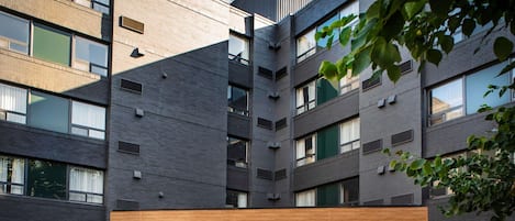A multi-story hotel with a modern design, featuring a covered entrance and a landscaped garden area.