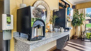 Una estación de café con una máquina de café, un dispensador de agua y un espejo decorativo.