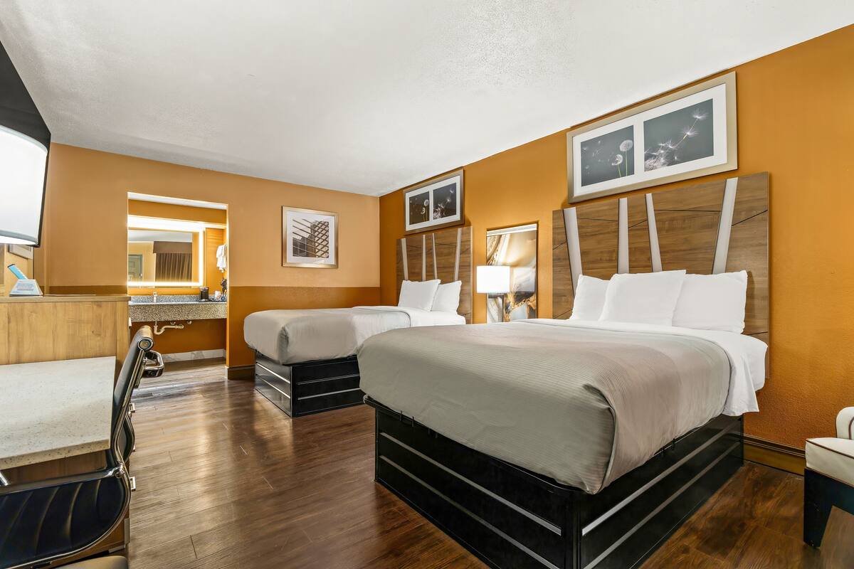 Ett hotellrum med en stor säng, en mindre säng, ett skrivbord och en stol.