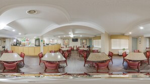 A spacious dining area with multiple tables and chairs, a kitchen area, and a counter with a cash register.