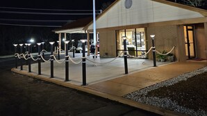 A building with a flagpole, a covered area with lights, and a gated entrance.