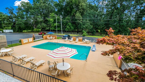 A pool area with lounge chairs, a table, and an umbrella.