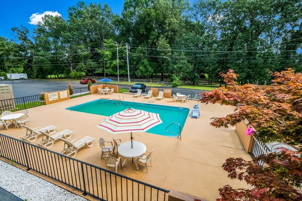 A pool area with lounge chairs, a table, and an umbrella.