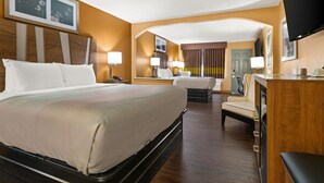 Habitación de hotel con una cama grande, un escritorio, una silla y un televisor.