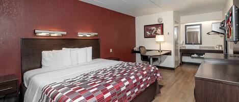 Una habitación de hotel con cama, escritorio, silla, televisor y baño.