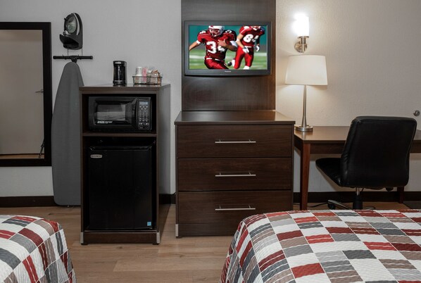 Une chambre d’hôtel équipée d’un lit, d’un bureau, d’une télévision, d’un four à micro-ondes et d’un réfrigérateur.