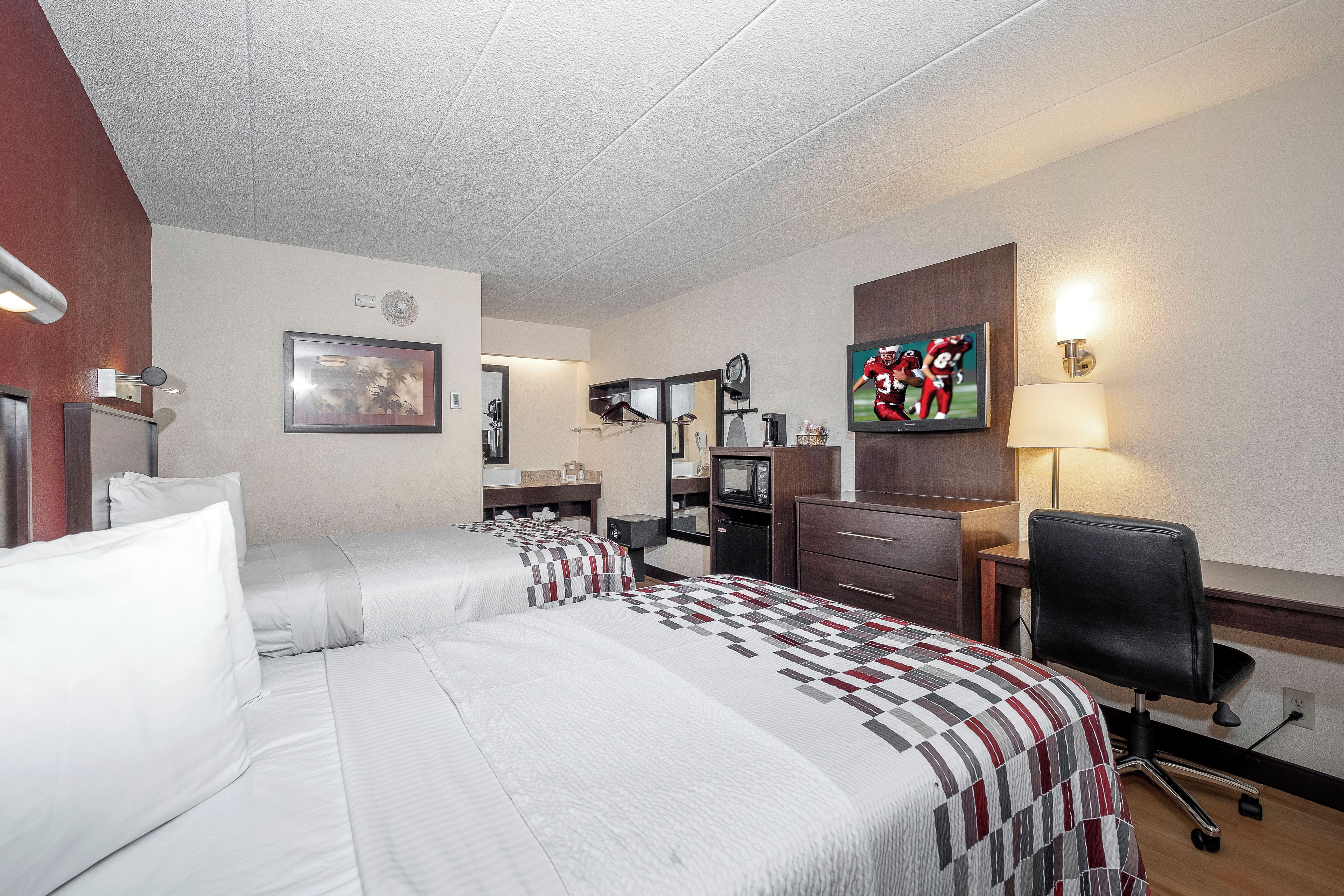 Une chambre d’hôtel équipée d’un lit, d’un bureau, d’une chaise, d’une télévision et d’un four à micro-ondes.