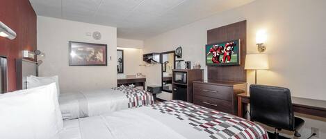 Une chambre d’hôtel équipée d’un lit, d’un bureau, d’une chaise, d’une télévision et d’un four à micro-ondes.