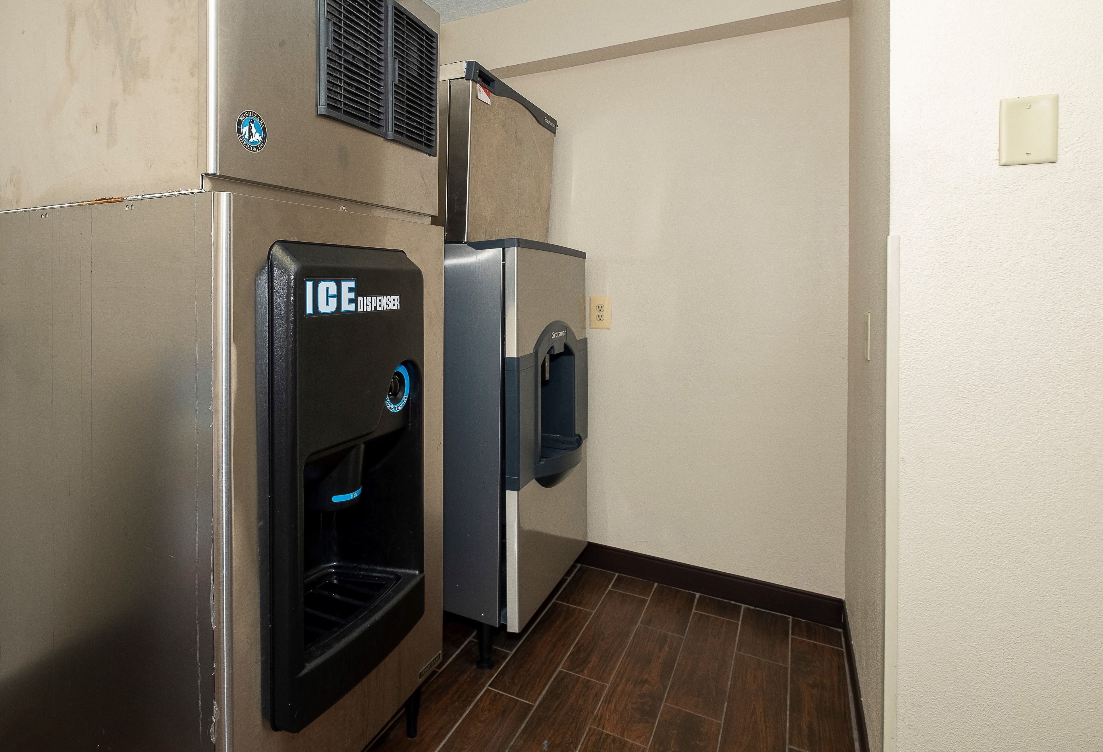A commercial ice dispenser and a refrigerator in a hallway.