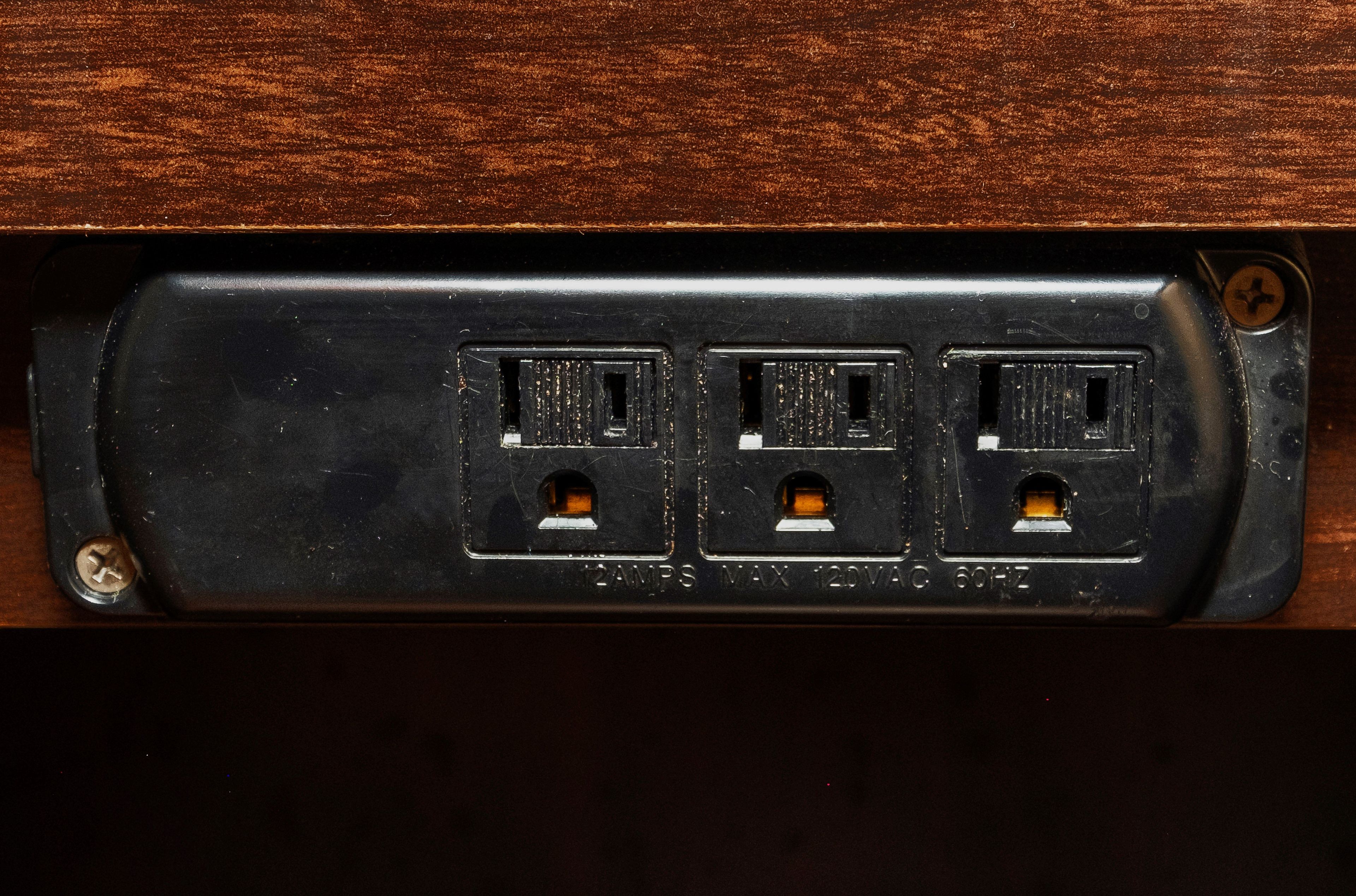 A black electrical panel with three sockets, labeled '12AMP MAX 120VAC 60HZ'.