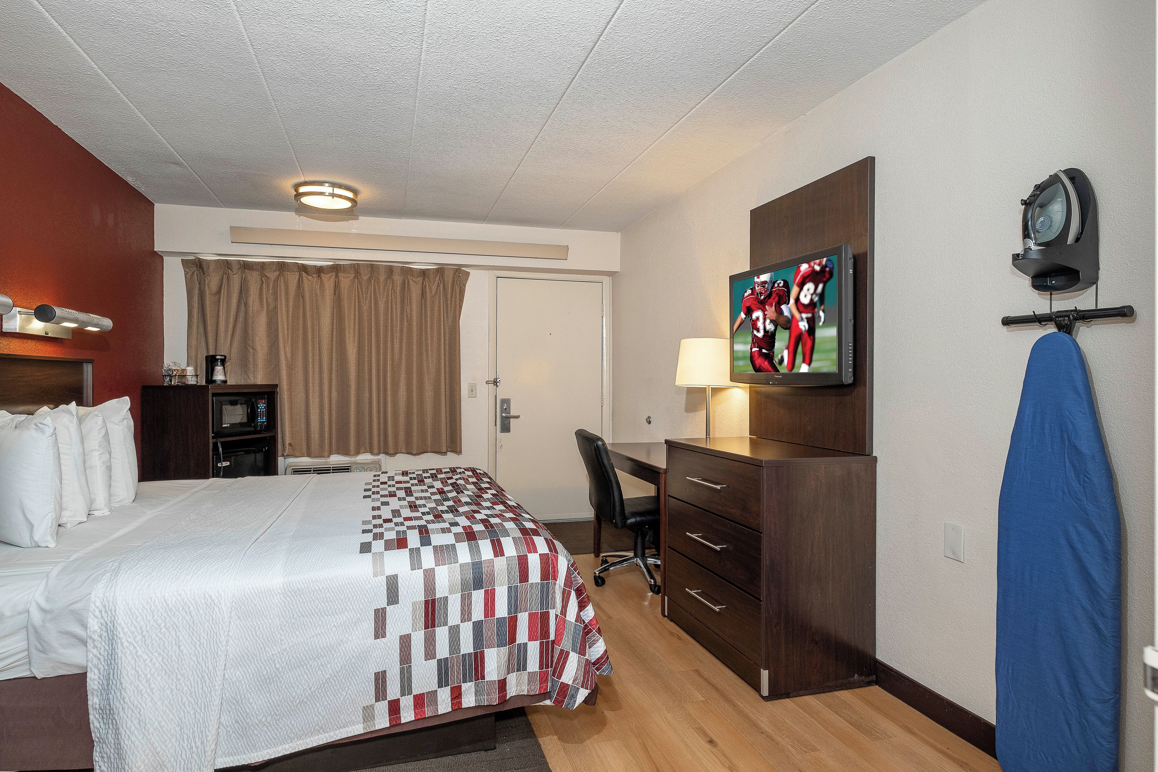 A hotel room with a bed, a desk, a television, and a wardrobe.