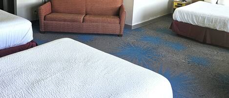 Habitación de hotel con dos camas, un sofá y piso alfombrado.