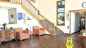 A spacious living area with a wooden staircase, a sofa, a coffee table, and a dining table.