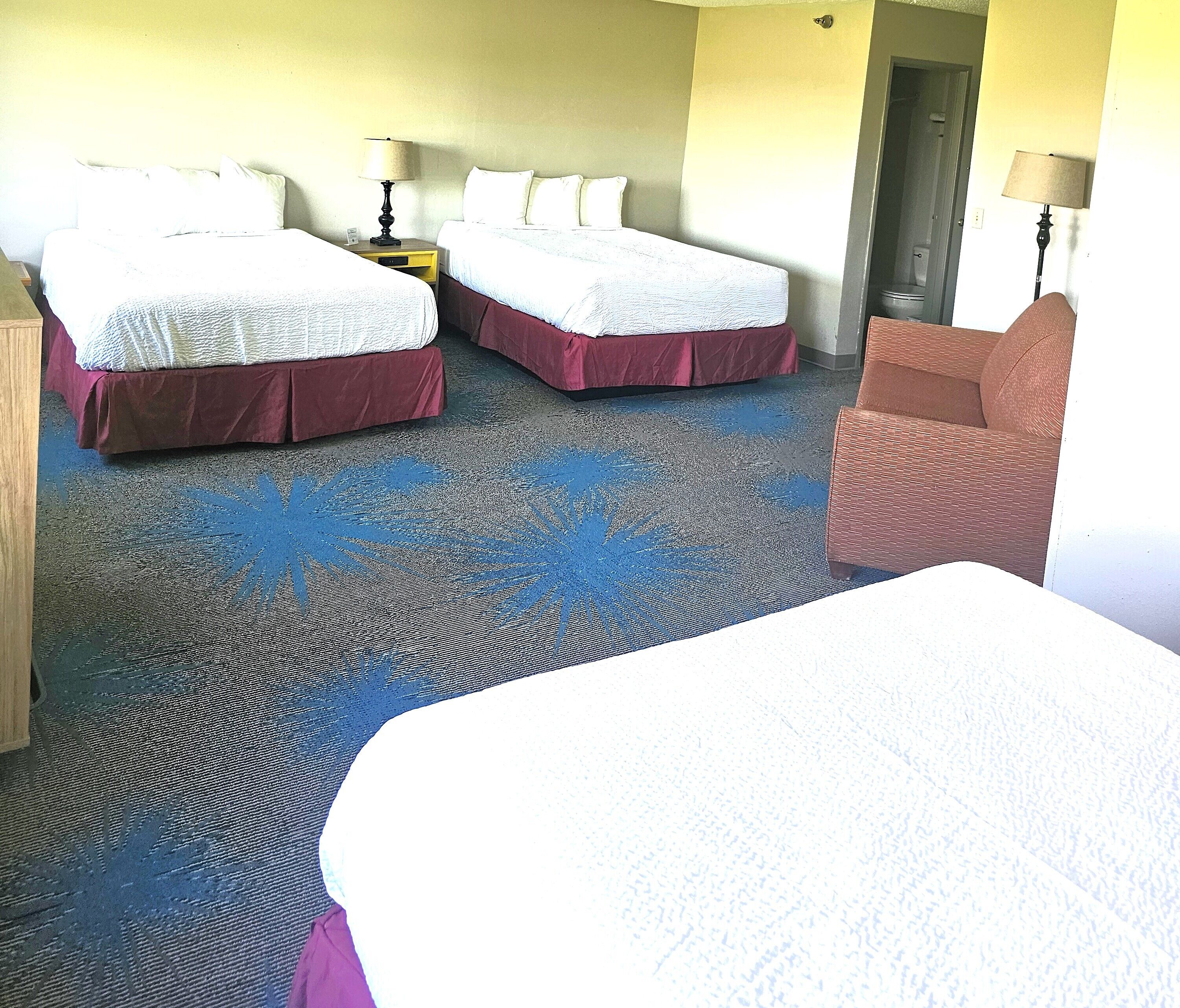 A hotel room with two beds, a chair, and a small table.