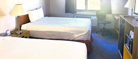 Habitación de hotel con dos camas, un escritorio, una silla, una lámpara y una ventana con cortinas.