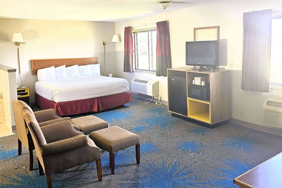 Una habitación de hotel con una cama, televisión, escritorio, silla y lámpara de escritorio.