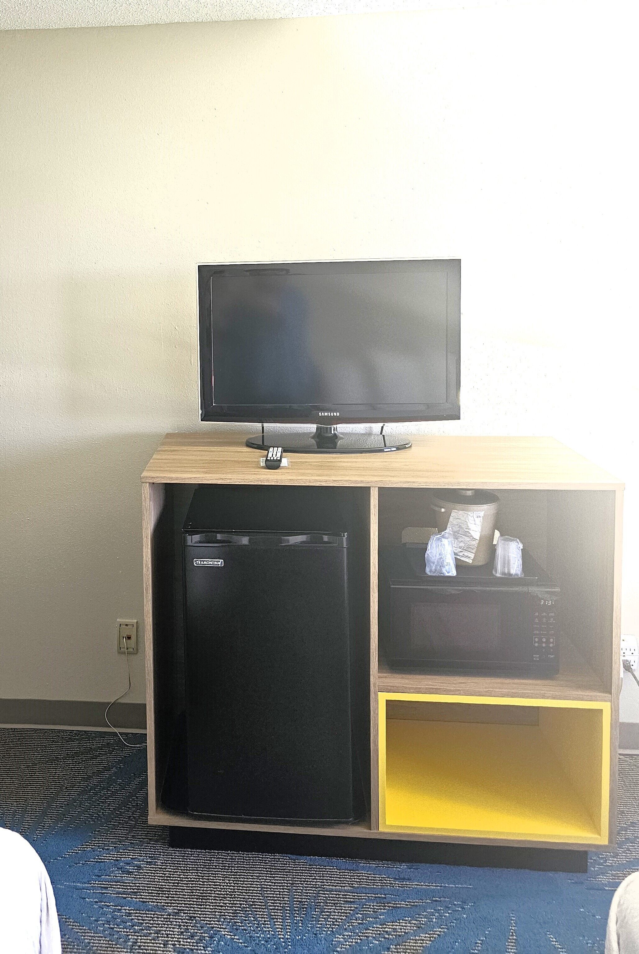 A compact entertainment unit with a flat-screen TV, a small refrigerator, and a microwave.