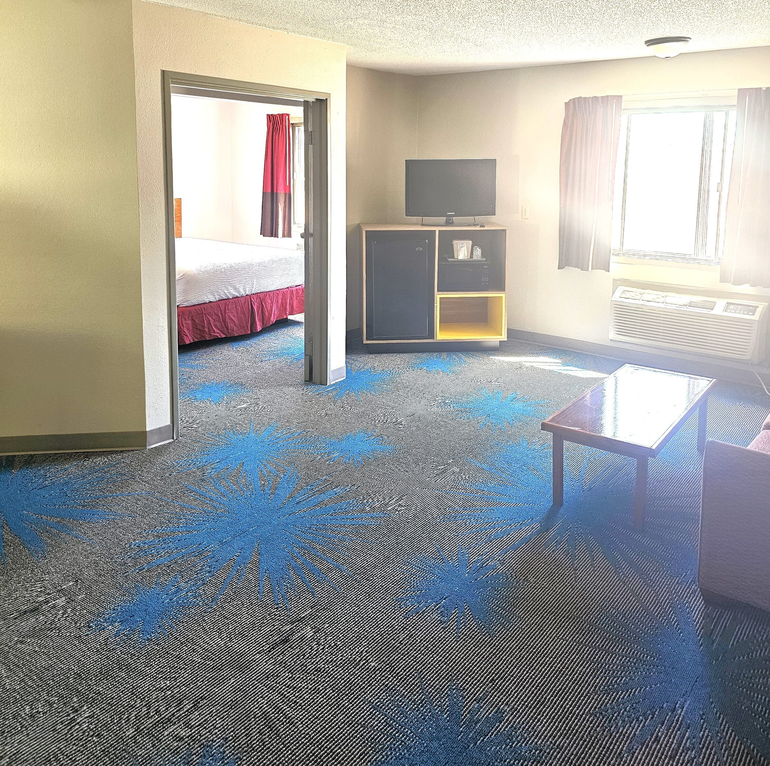 A hotel room with a bed, a TV, a small cabinet, and a window.