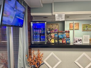 A snack and beverage corner with a refrigerated display, snack bags, and a TV screen.