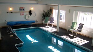 An indoor swimming pool with a lifeguard chair, a no diving sign, and a no diving allowed sign.