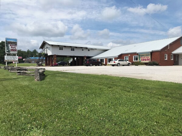 A motel with a covered parking area, a sign for Baxter Park Inn, and a grassy foreground.