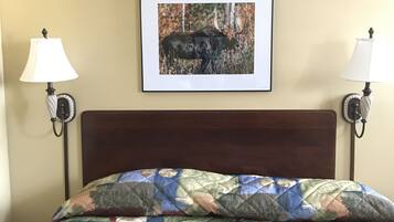 A hotel room with a bed, a framed picture of a bull on the wall, and two bedside lamps.