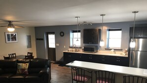 A modern kitchen with a central island, black cabinets, stainless steel appliances, and pendant lighting.