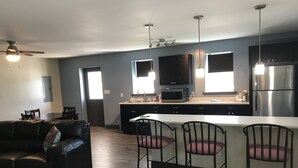 A modern kitchen with a central island, built-in appliances, and pendant lighting.