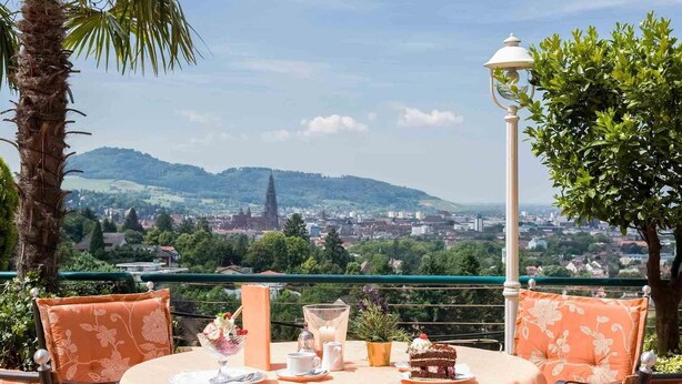 Une table dressée pour deux personnes, avec vue sur le paysage urbain et les collines en arrière-plan.