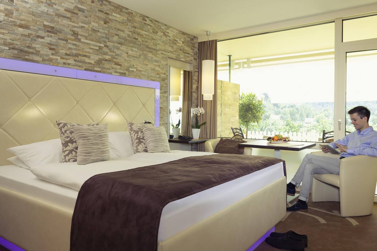 Ein Hotelzimmer mit einem großen Bett, einem Schreibtisch und Blick ins Freie.