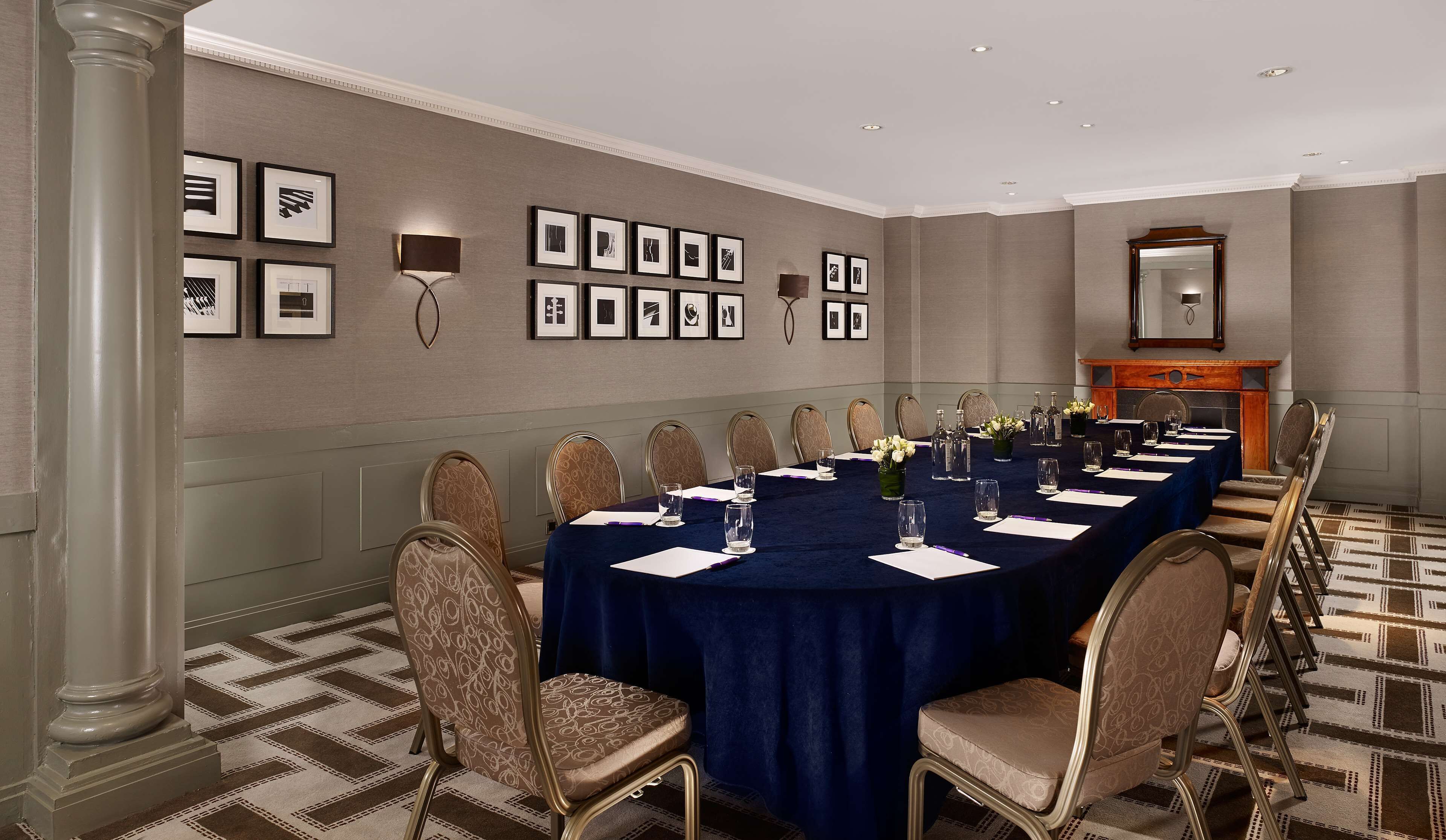 A conference room with a long table, chairs, and framed pictures on the wall.