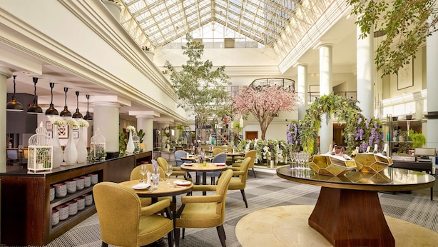 A spacious hotel lobby with a high glass ceiling, multiple seating areas, and indoor plants. - Hyatt Regency Birmingham (Birmingham)