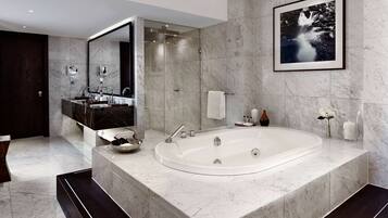 A modern bathroom with a large bathtub, a double vanity with a mirror, and a framed artwork on the wall.