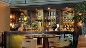 A bar area with a round table, bar stools, and shelves stocked with bottles. - Hyatt Regency Birmingham (Birmingham)