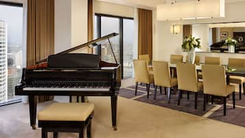 Un magnifique piano à queue se trouve dans une pièce spacieuse, qui comprend un coin repas et une grande fenêtre donnant sur la ville.